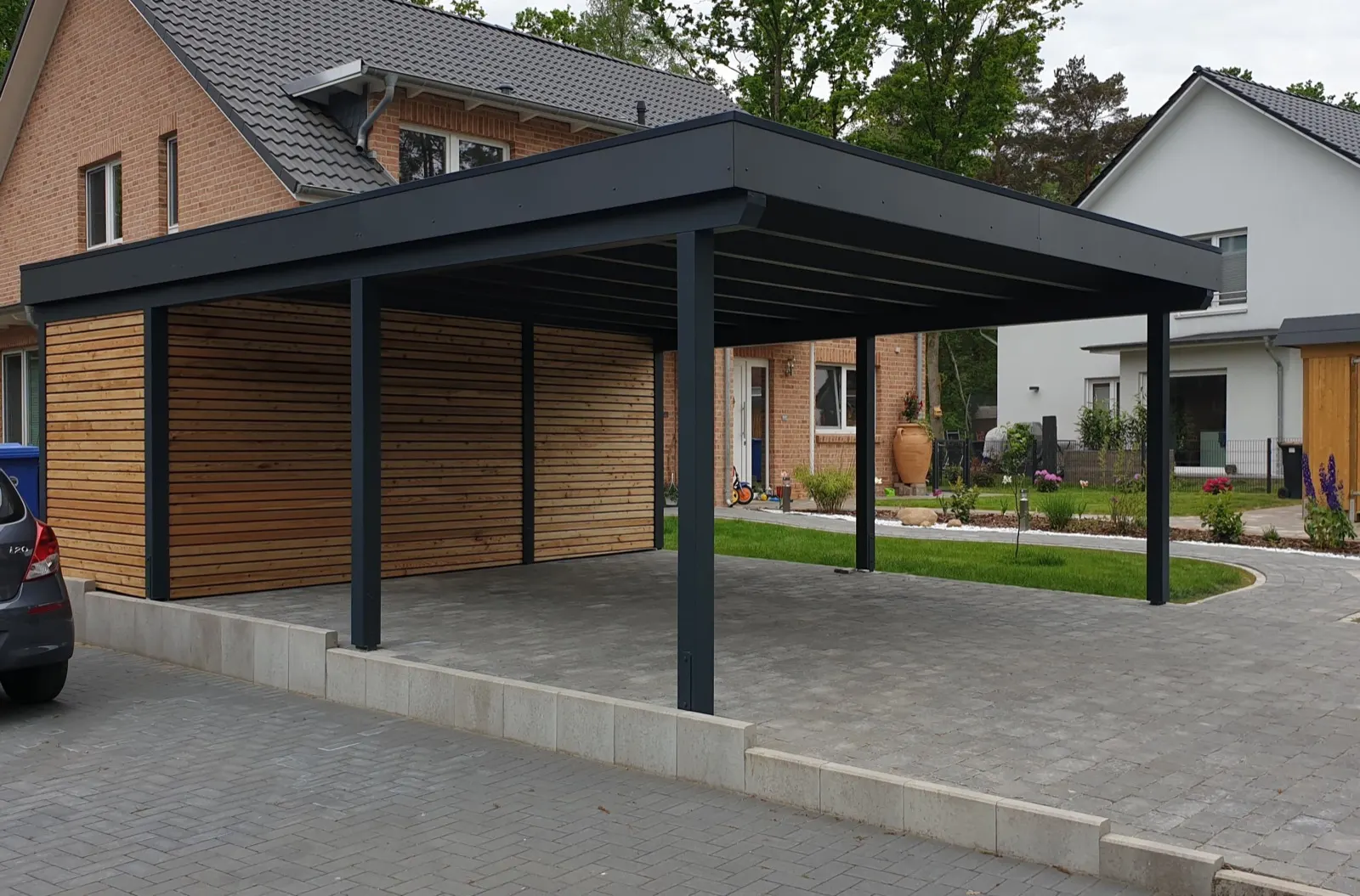 Freistehender Doppelcarport mit anthrazitfarbenem Flachdach und Wänden aus Lärche-Rhombusleisten